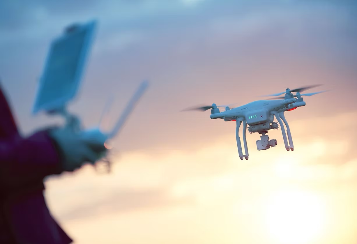 Drone pilot flying a quadcopter at sunset